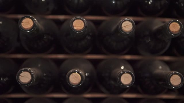 Unlabeled Wine bottles on the shelf of a cellar for aging - closeup, tracking shot