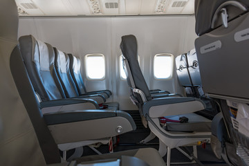 Seats, lunch trays with seat belts inside empty commercial airplane