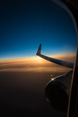 View through window of airplane – sunset over clouds