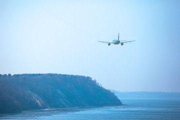 Airplane flies over the sea and the picturesque beach, toned