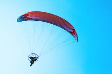 Paraglider flying in the bright blue sky