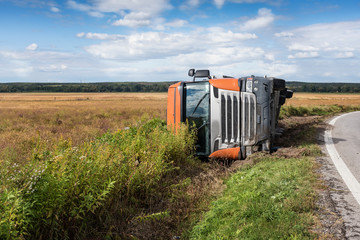 Front of truck that is overturned into field next to road