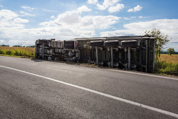 Chassis of overturned truck in field next to road