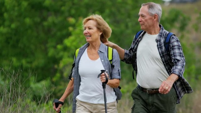 Healthy retired Caucasian American couple enjoying their vacation hiking to keep fit in the countryside 