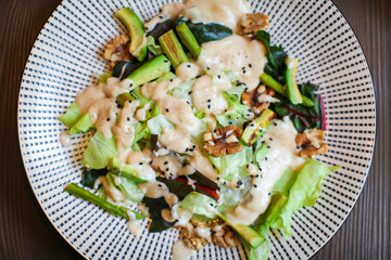 Close up Healthy salad with avocado , walnuts and grilled asparagus . Vegan food on dark wooden table.