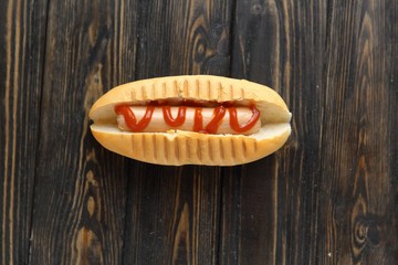 hotdog with tomato sauce on dark wooden background.photo with copy space