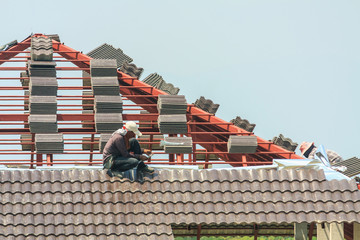 Construction roofer installing roof tiles at house building site © Kwangmoozaa