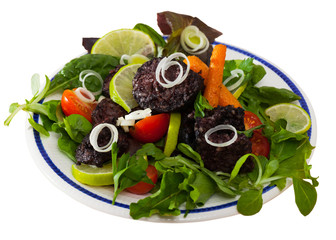 Blood sausage with different greens, tomatoes and lemon served at plate