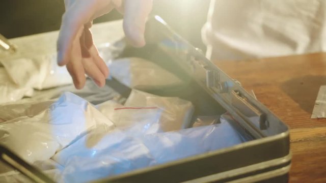 drug dealer is packing drugs into suitcase. Close-up. Abuse of drugs. Criminal Business