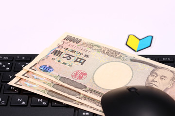 パソコンのキーボードと一万円札と初心者マーク