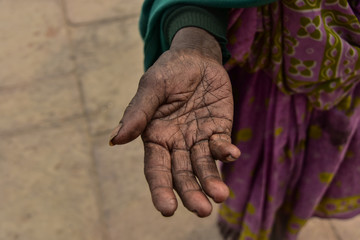 インドのバラナシ　ガンジス川沿いのガートを歩く貧しい老婆　物を乞う手のひらのクローズアップ写真