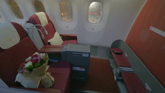 Wide steadicam shot of a jet airplane interior view without people seated inside the cabin, first class. Waving curtains