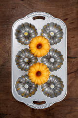 Two Small orange Bundt cakes on empty metal cooking mould, top view, flat lay