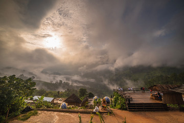 In the morning, Clouds and fog covered densely. People are watching the sunrise on the top of a mountain, which is a beautiful tourist attraction