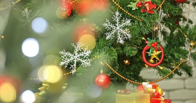 Close up scene VDO of blurred bokeh Christmas tree, there is beautiful Christmas tree decorated by gorgeous ornaments such as star, snowflake, light and holly at background, Christmas theme