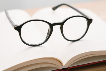 Black glasses on notebook on the table with blurred background. Close-up glasses.