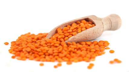 Red lentils in the wooden spoon, isolated on white background
