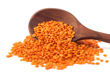 Red lentils in the wooden spoon, isolated on white background