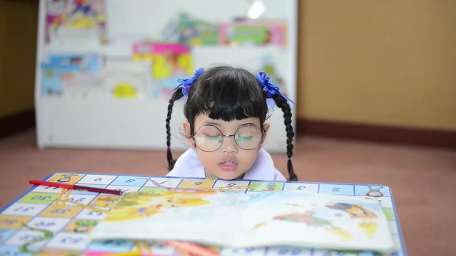 Cute child Asian girl doing homework and reading a book. Kid enjoy learning with happiness at home. Clever,Education and smart learning concept