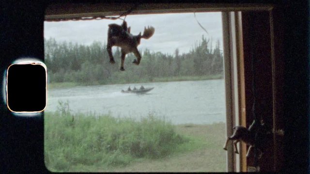 Super 8 film footage window view of a boat passing by with a moose toy in foreground.