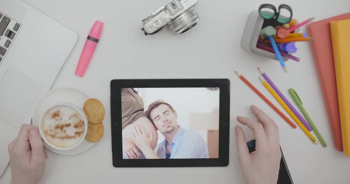 Top view looking family photos on tablet screen on desktop