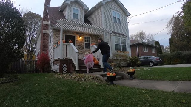 young dad and happy little girl in princess costume Trick or Treating on Halloween
