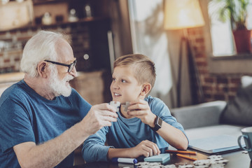 Handsome boy collecting puzzles with granddad