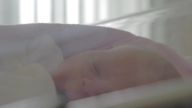 Close up shot of a newborn baby with blue eyes falling asleep while in her crib in the hospital