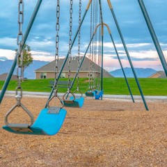 Blue swing with homes mountain and sky view