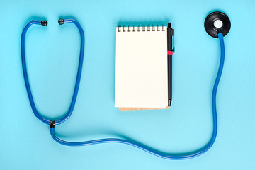 Blue stethoscope and a Notepad on a blue background