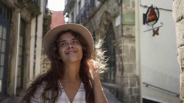 Cheerful young lady walking on street in old city centre Porto, Portugal in sunny day