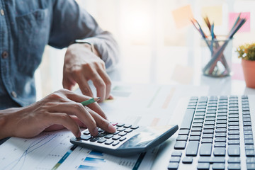 Close up of businessman or accountant hand holding pen working on calculator to calculate business...