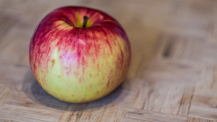One fresh apple on bamboo cutting board close up