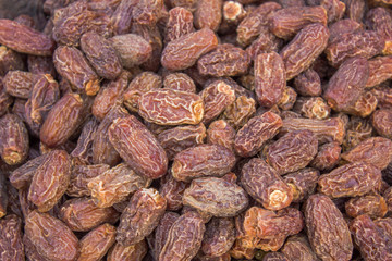 many dried dates lie in a heap. brown wrinkled dates. natural texture