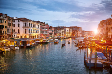 Fototapeta na wymiar Canal Grande with boats and lights in Venice at Sunset. Next to famous Rialto Bridge and the Street 