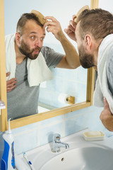 Man using comb in bathroom