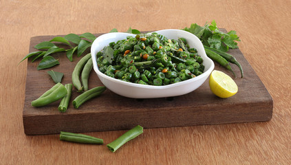 Green bean curry, a South Indian Traditional and Popular Vegetarian Side Dish in a Tray on a Wooden Board