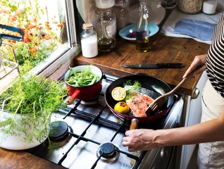 Keuken foto achterwand Koken Vrouw die zalm in een pan kookt