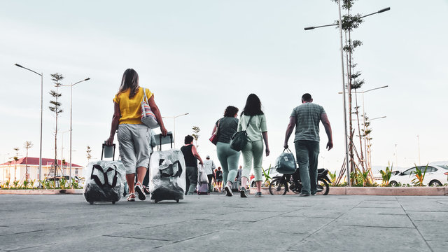 Crowd of tourists with suitcases and bogage. View from the back. Travel as a lifestyle