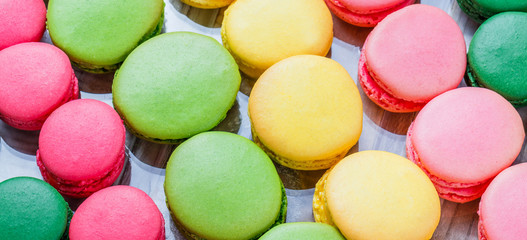 Fototapeta na wymiar Colorful tasty macaroons on wooden table with flowers, a french sweet delicacy, macaroon texture. Top view, flat lay