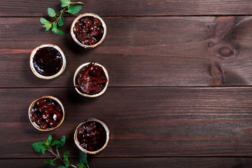 Berries and fruits jam, marmalade on dark wooden background. Top view