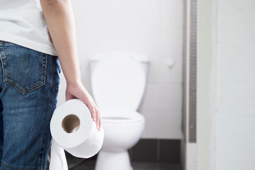 Asian boy sitting on toilet bowl holding tissue paper  - health problem concept