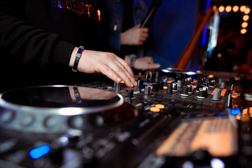 club DJ in headphones with sound mixer in nightclub