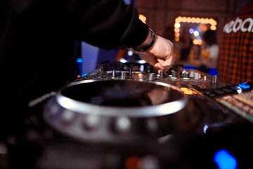 control DJ for mixing music with blurred people dancing at party in nightclub