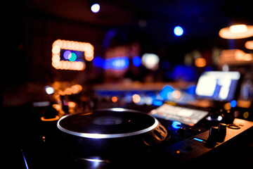 Fototapeta na wymiar DJ behind the decks in a nightclub. DJ spinning plate. people dancing in a nightclub. disco