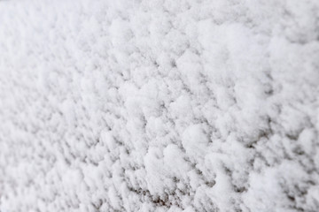 Texture of adhering snow on a vertical surface, close-up view, selective focus.