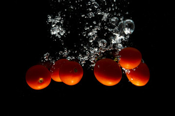 Red tomato on black background with water splash