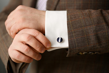 Male arm in brown suit set stud closeup