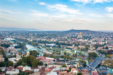 Tbilisi cityscape from a view point on a clear day showing old and modern architecture with mountains in the background, Georgia