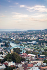 Tbilisi cityscape from a view point in the lights of sunset showing old and modern architecture with mountains in the background, Georgia